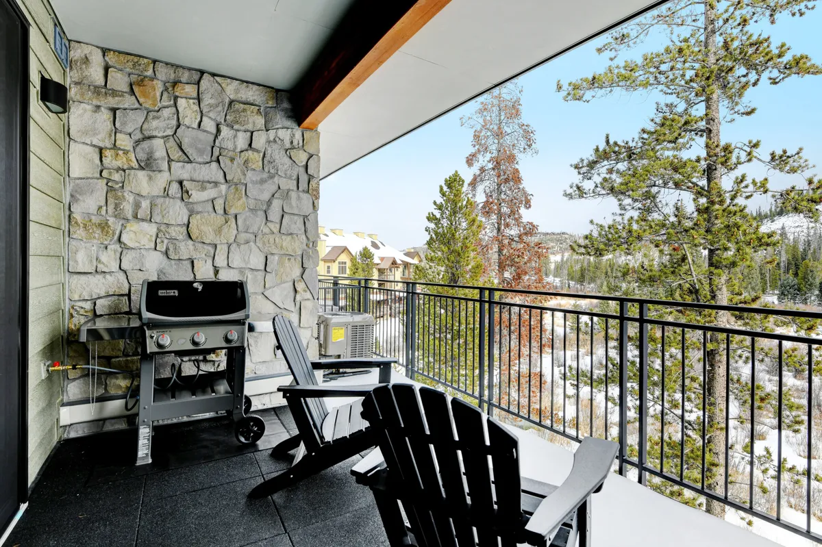 A private patio with Adirondack chairs, a barbecue grill, and scenic mountain and forest views—a welcoming outdoor extension of the living space, ideal for morning coffee, grilling, or sharing stories after a day of adventure.