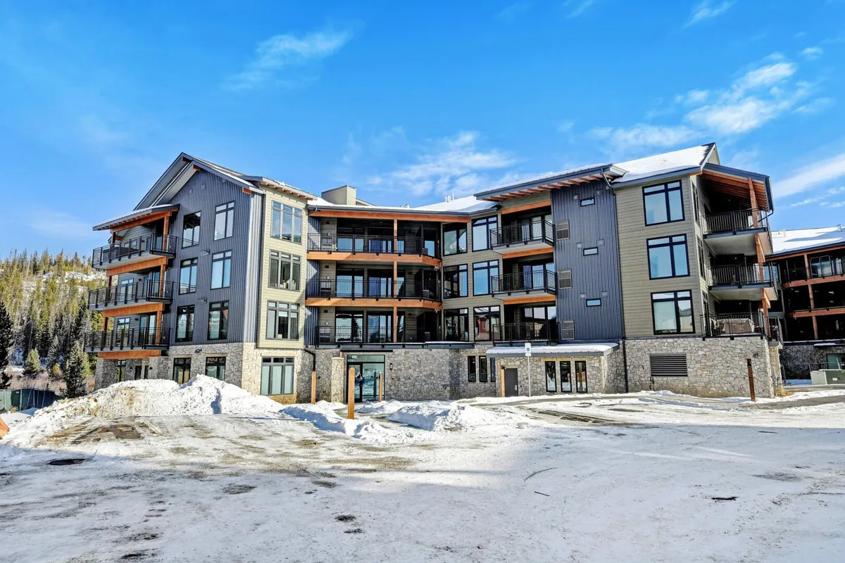 An inviting exterior shot of the Timber Fox property, set against a snow-covered landscape. The modern architecture features large windows and warm wooden accents, suggesting both accessibility to adventure and a welcoming retreat after a day outdoors.