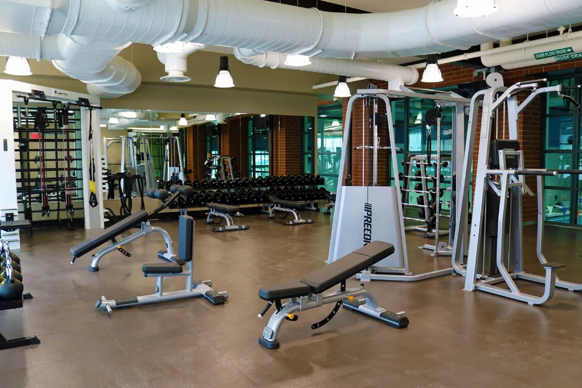 A well-equipped gym with dumbbells, weight machines, an incline bench, and mats, all in a bright, motivational setting. This space supports a healthy, active lifestyle with opportunities for personal fitness and stress relief.